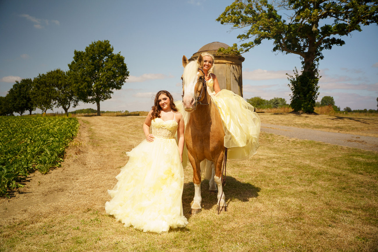2 girls yellow prom dresses with a horse